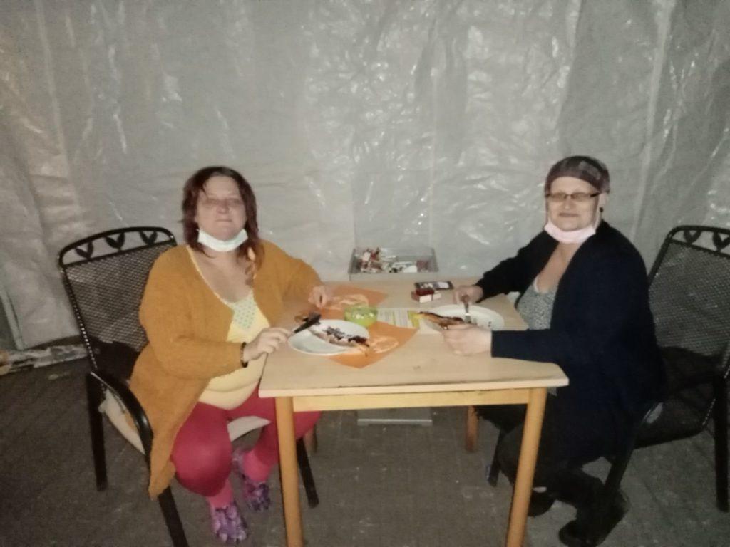 An einem Tisch essen zwei Damen jeweils einen Pfannkuchen und freuen sich sichtbar darüber.