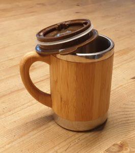Das Bild zeigt eine Tasse mit Deckel aus Bambus und Aluminium, in die unterwegs Kaffe oder ein Getränk gekauft und eingefüllt werden kann.