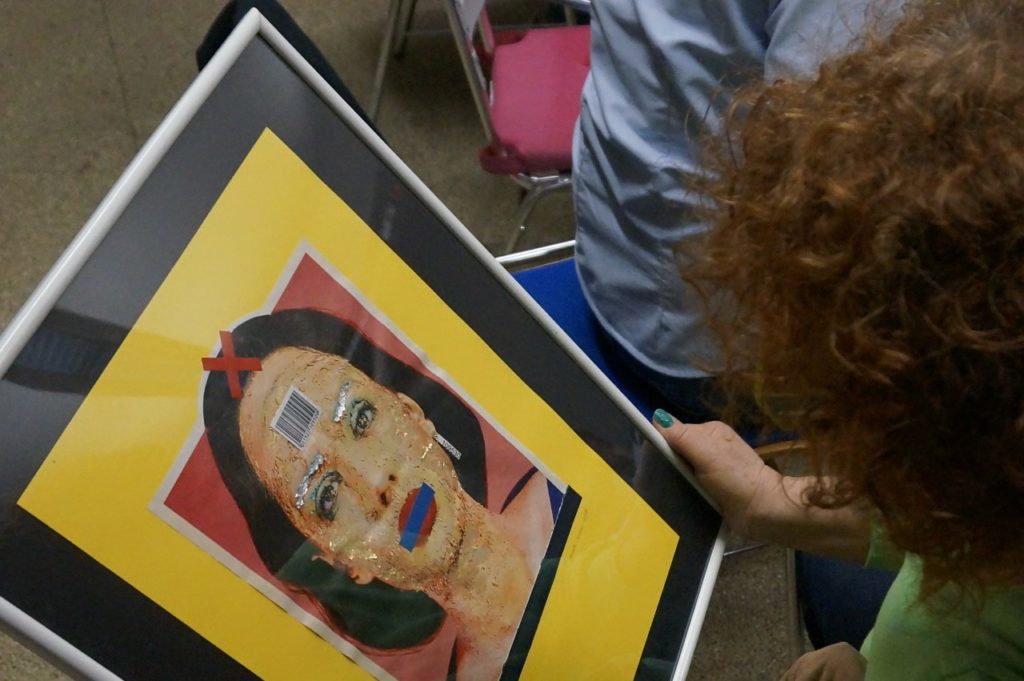 Eine Teilnehmerin betrachtet ein anderes Kunstwerk. Das Kunstwerk stellt den Kopf einer Frau da, die eine Nummer und einen Barcode trägt.