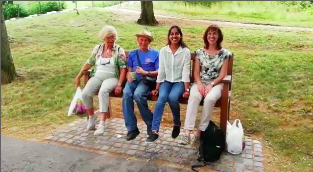 Rita, Gernot, Shruti und Sylvie auf der Bank. Sie wackeln mit den Beinen.