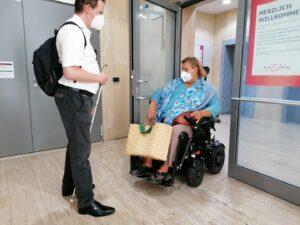 Kirsten und Boris im Eingengsbereich zum Ärztezentrum - die schwere Tür bekommt Kirsten nur mit Mühe alleine auf.