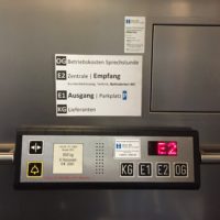 Gut erkennbare Anweisungen im Fahrstuhl. Nun sind die einzelnen Informationen zu den Stockwerken groß auf einem Aufkleber dargestellt.