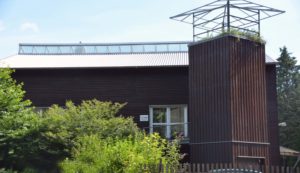 Das Bild zeigt die Samendarre im Forstamt Wolfgang, ein Holzgebäude mit kleinem Dachgarten.
