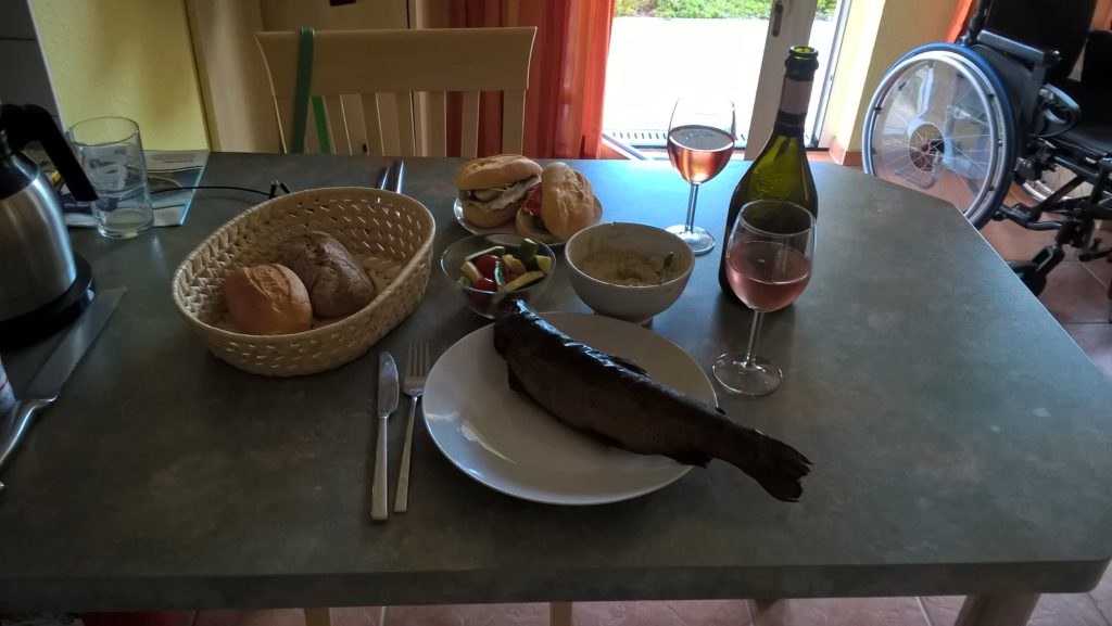 Ein gebratener Fisch auf einem Teller und Brot und Wein