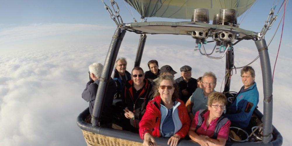 Das Bild zeigt Menschen während einer Ballonfahrt über den Wolken