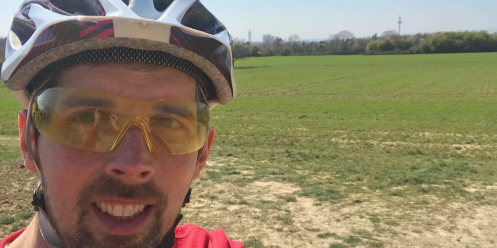 Daniel mit dem Fahrrad unterwegs. Hier ein Selfie. Er ist optimal ausgestattet mit Fahrradhelm und Brille.