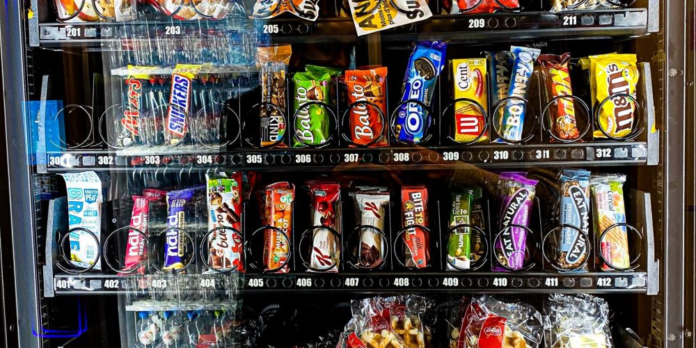 Das Bild zeigt einen Snack-Automaten von vorne. Chips, Schokoladenriegel und mehr sind zu sehen.