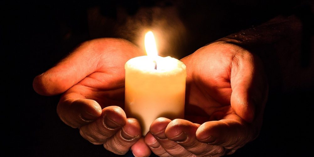 Zwei Hände halten eine Kerze als Zeichen des Mitgefühls für die Opfer des Attentats in Hanau am 19.02.2020