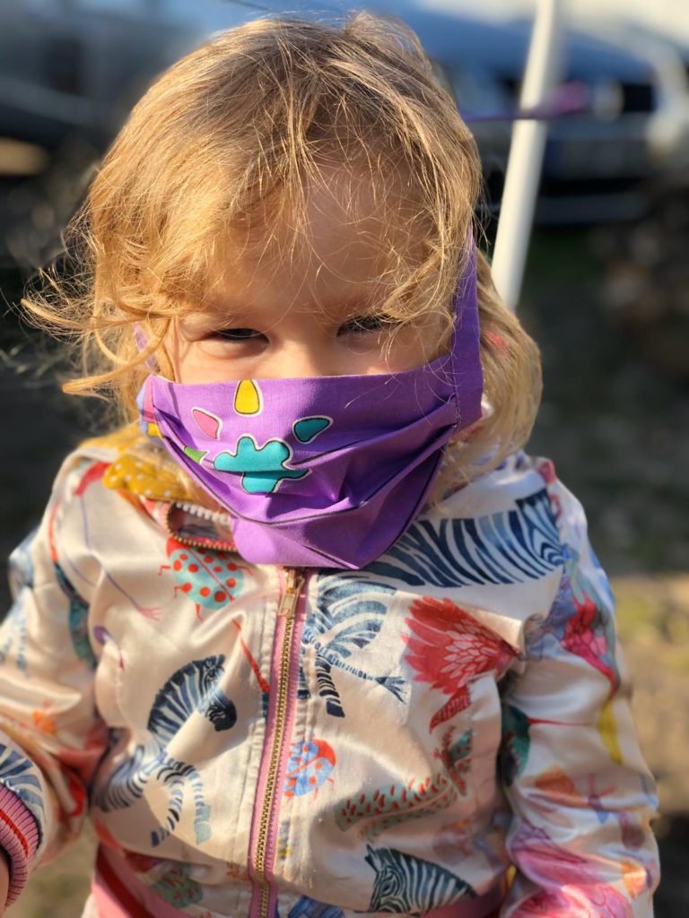 Ein Kind mit lila farbener Maske.